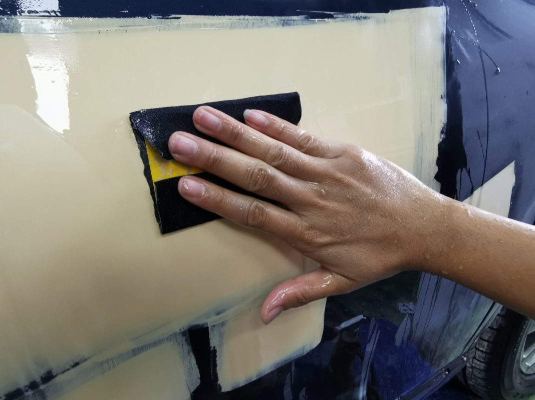Wet-sanding the X-Trail's panels to smooth the existing paintwork.