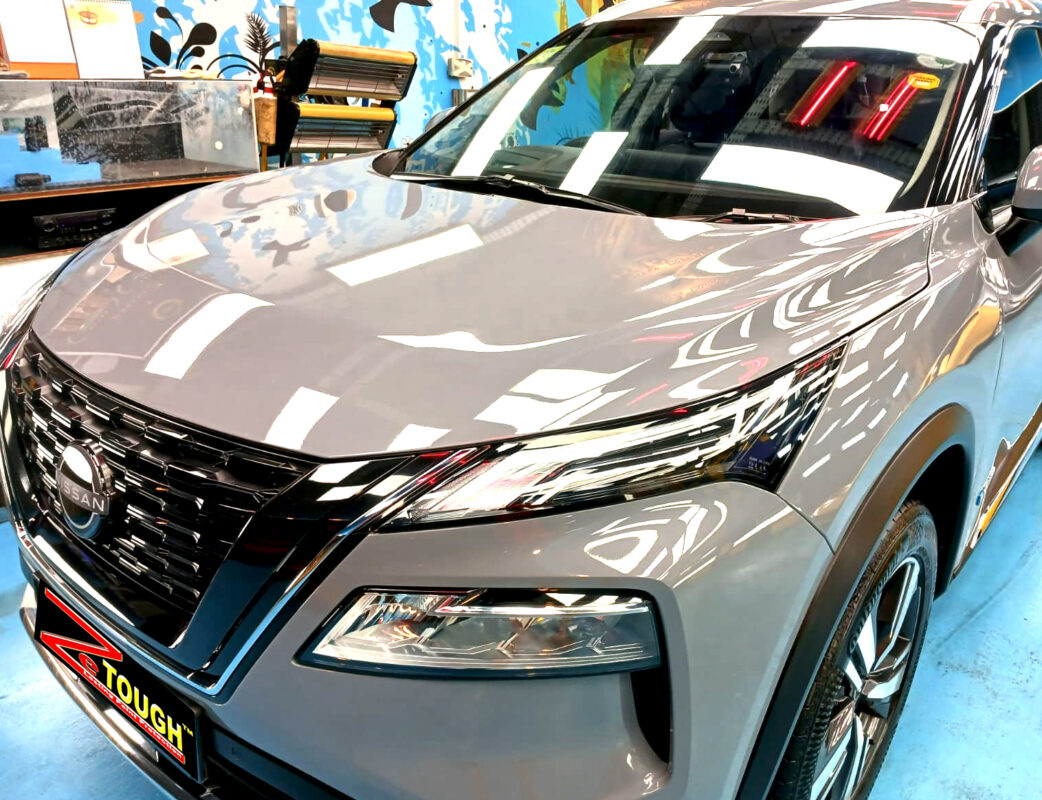 The Nissan X-Trail's coated paintwork under workshop lighting.