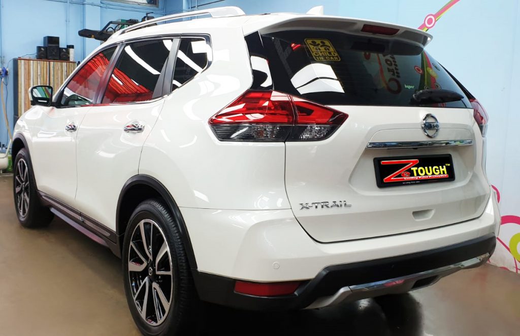 The coated bonnet of the X-Trail under workshop lighting.