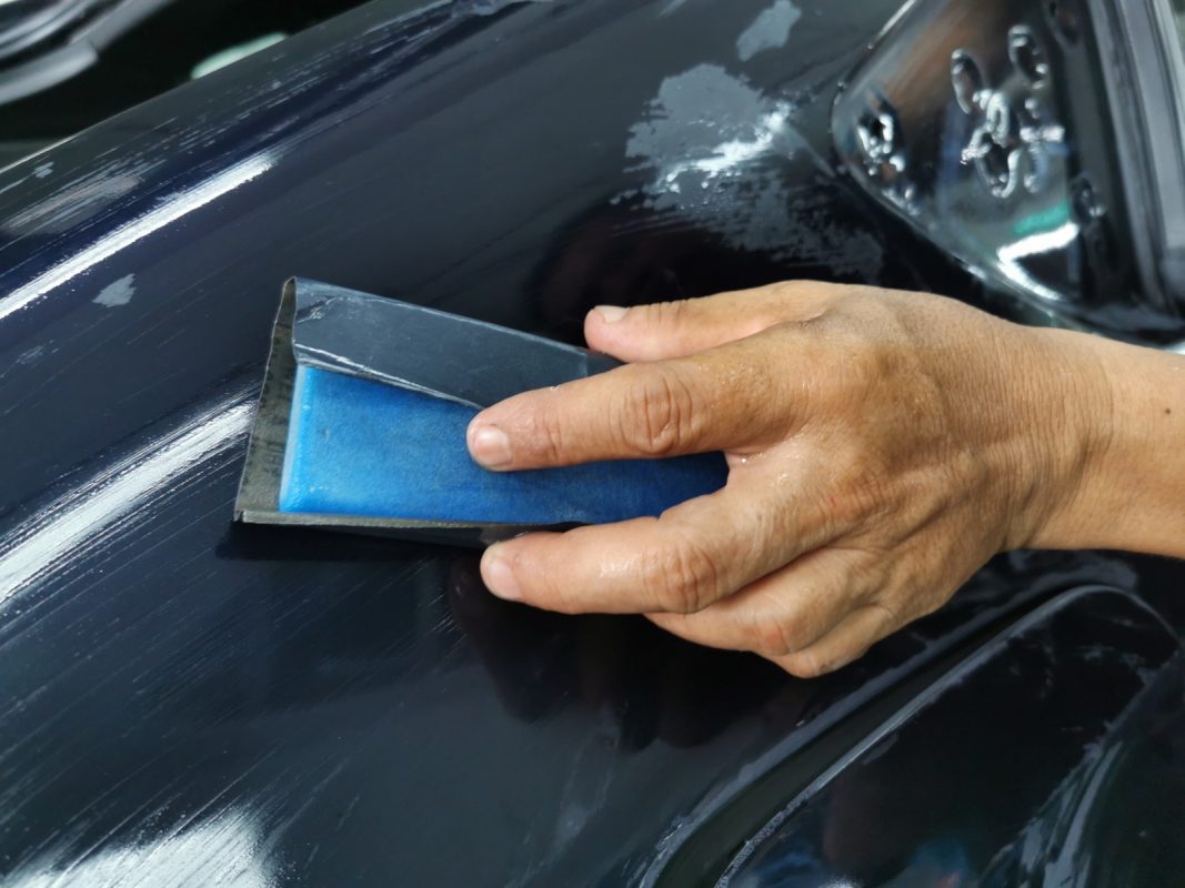 Wet-sanding the Insignia's panels to smooth the existing paintwork.