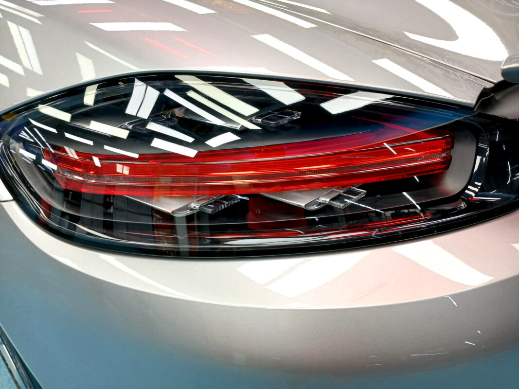 Close-up of the 718 Boxster's coated surface under workshop lighting.