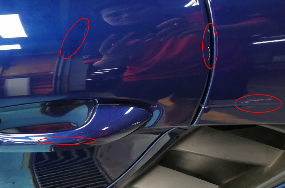 A second angle of the 718 Cayman on arrival, stone chips and scratches visible across the panels.