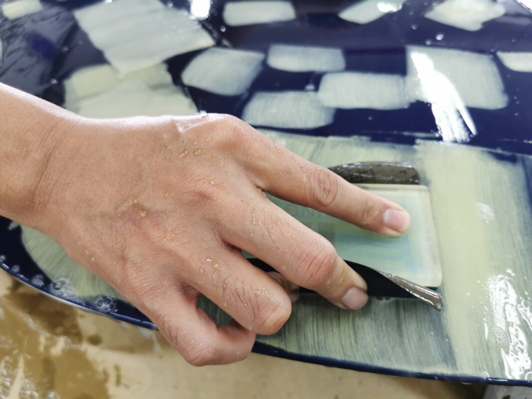 Wet-sanding a panel on the 718 Cayman to bring the surface smooth and level.