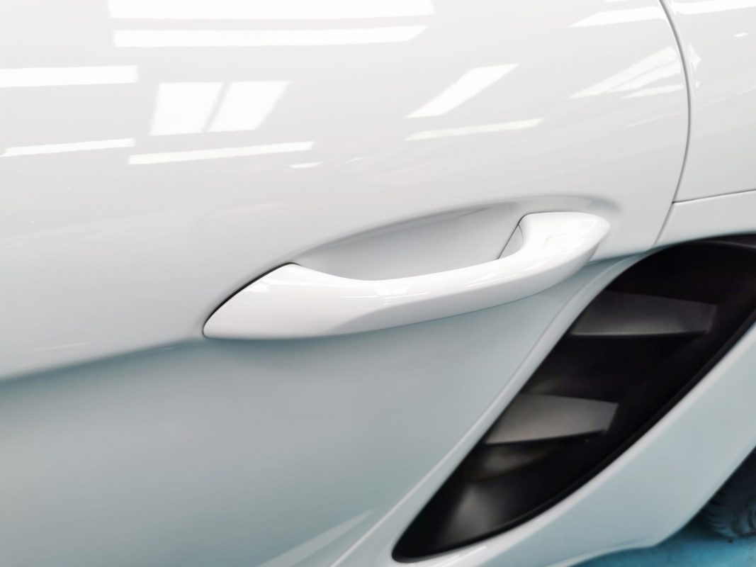 Rear three-quarter view of the 718 Cayman, glossy and protected.