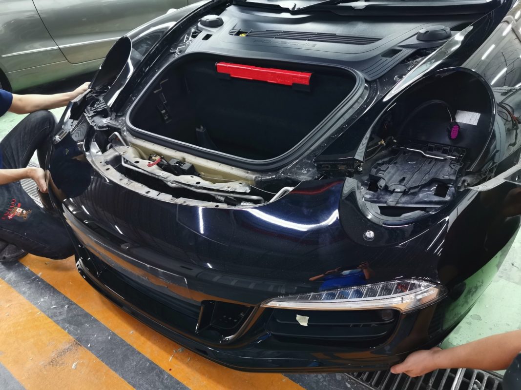 Bumpers and mirrors being dismantled from the Porsche 911 Carrera.