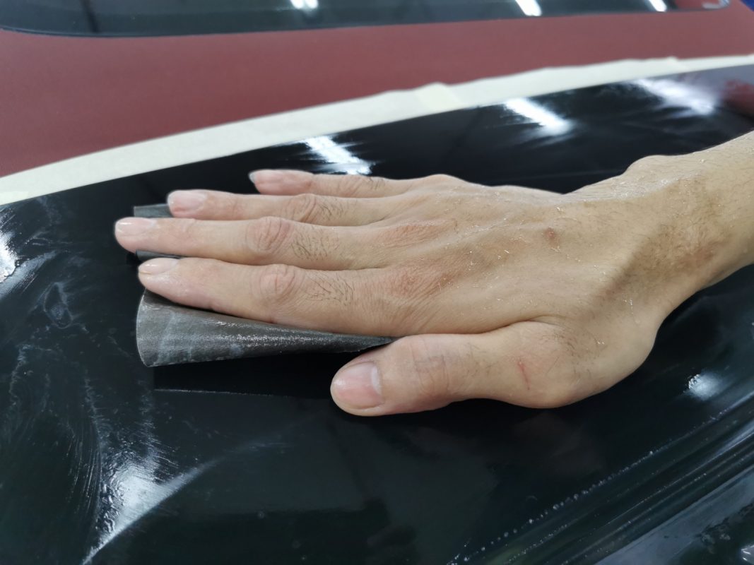 Wet-sanding the 911 Carrera's panels to smooth the existing paintwork.