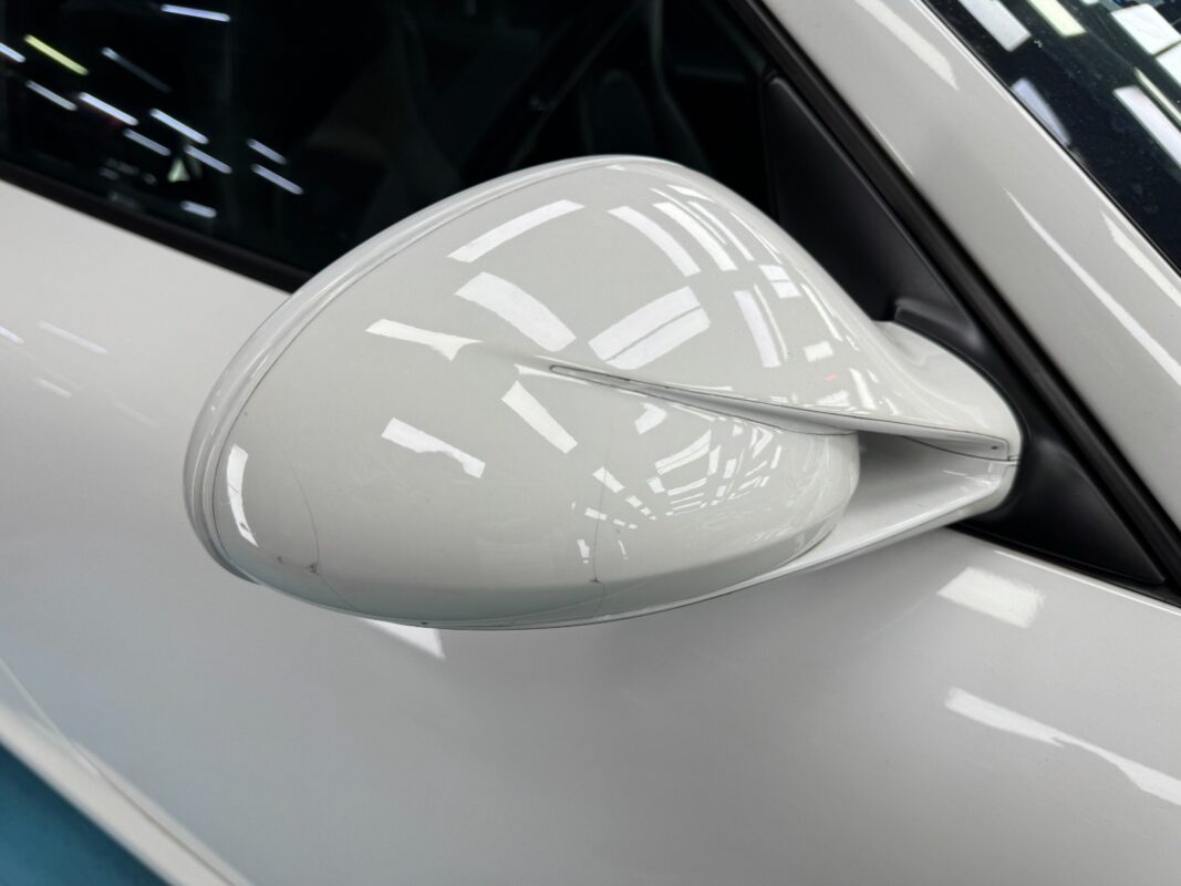 A close look at the original paintwork on the Porsche 911's mirror and door, showing the scratches.