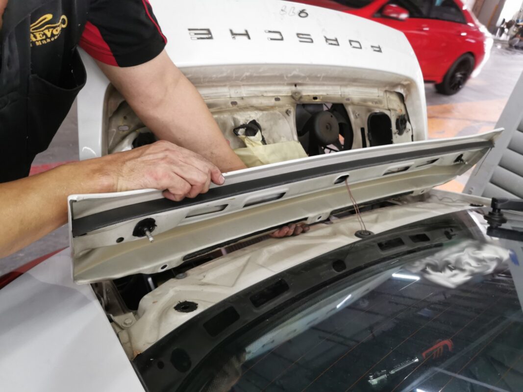 The Porsche 911 stripped down, with the engine cover lifted away for the respray.