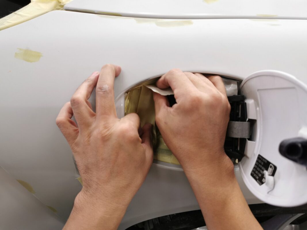 Masking the fuel filler area on the Porsche 911 before the spray booth.