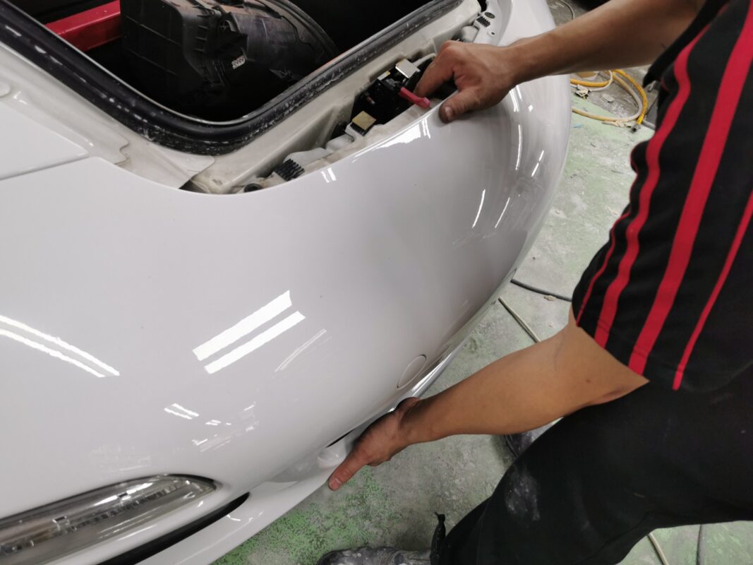 Refitting the front bumper on the Porsche 911 after painting.