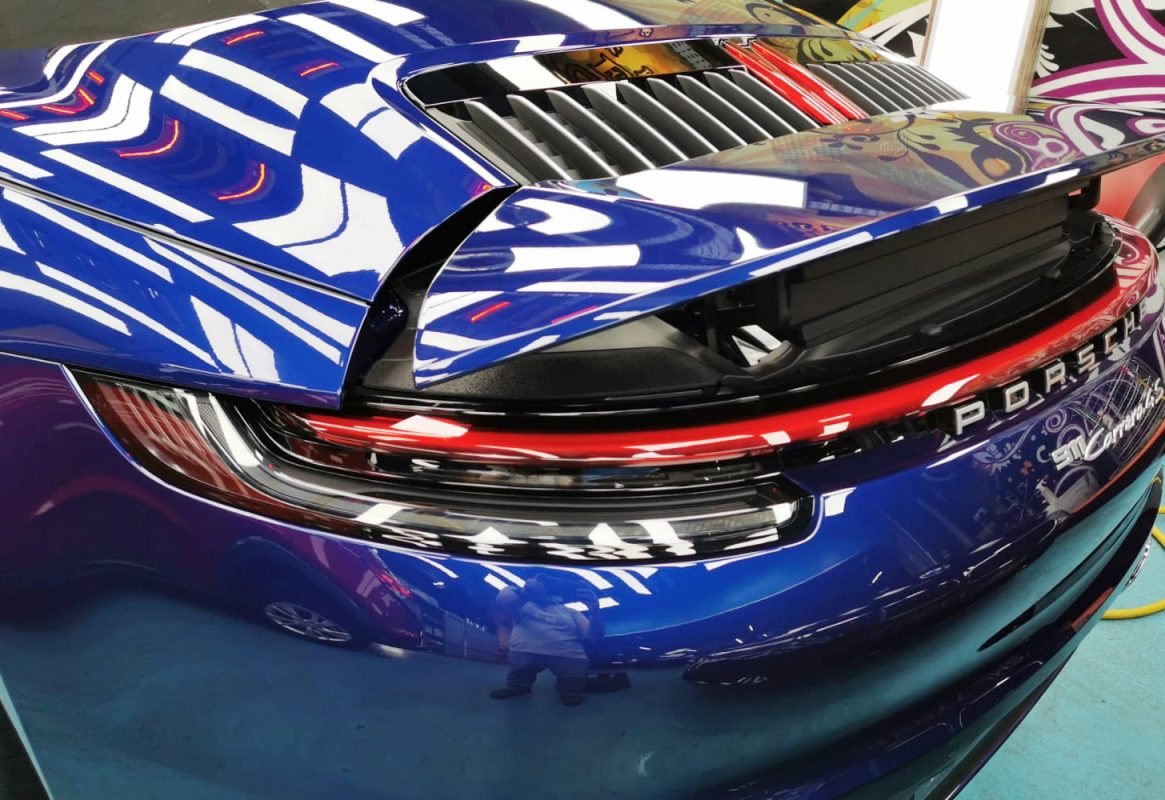 The coated bonnet of the Porsche 992 Cabriolet under workshop lighting.