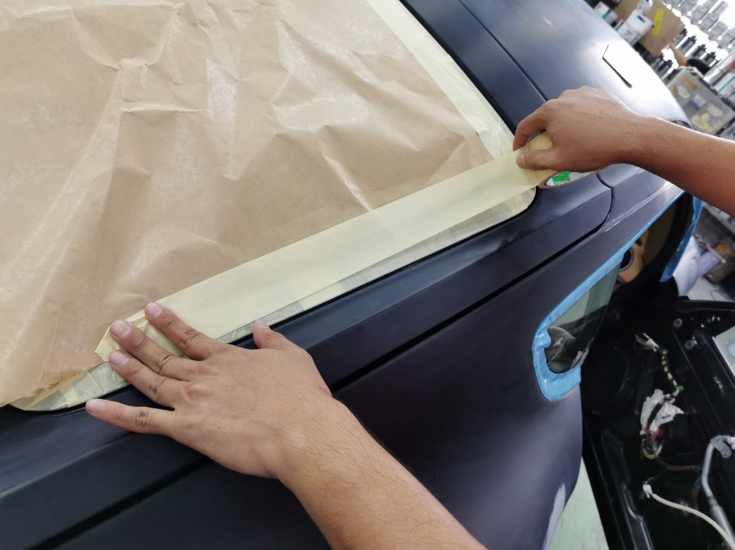 Non-painted surfaces being masked off on the Cayman before spraying.
