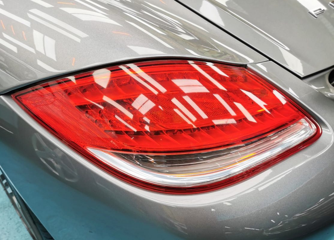 The coated bonnet of the Porsche Cayman under workshop lighting.