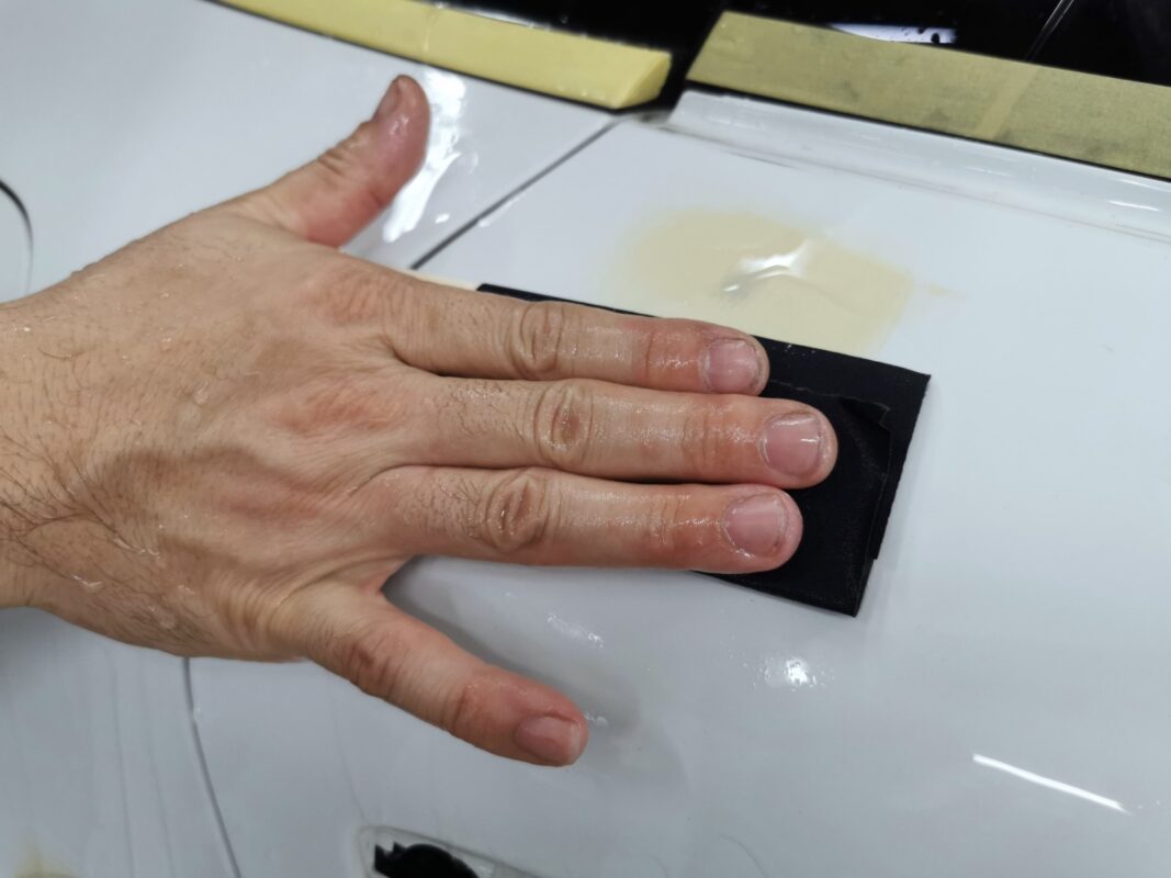 Wet-sanding the body of the Porsche Macan to smooth the surface.
