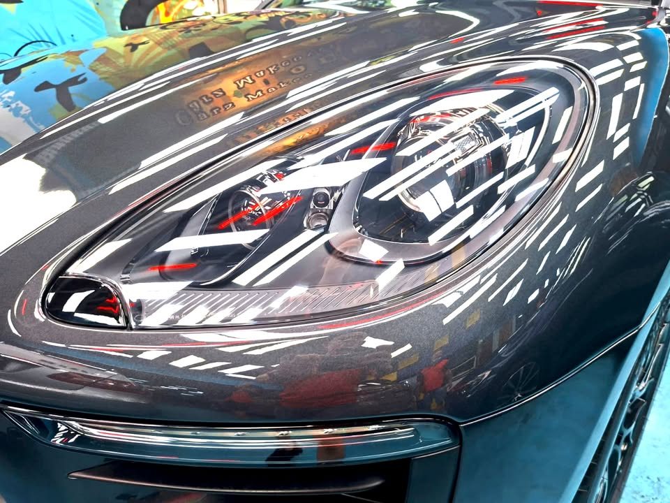 Close view of the Macan headlight and dark grey front wing.
