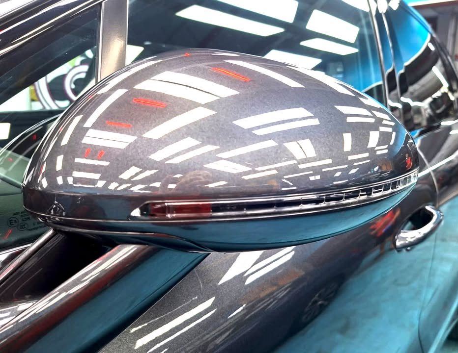Dark grey wing mirror on the Porsche Macan with light reflections.