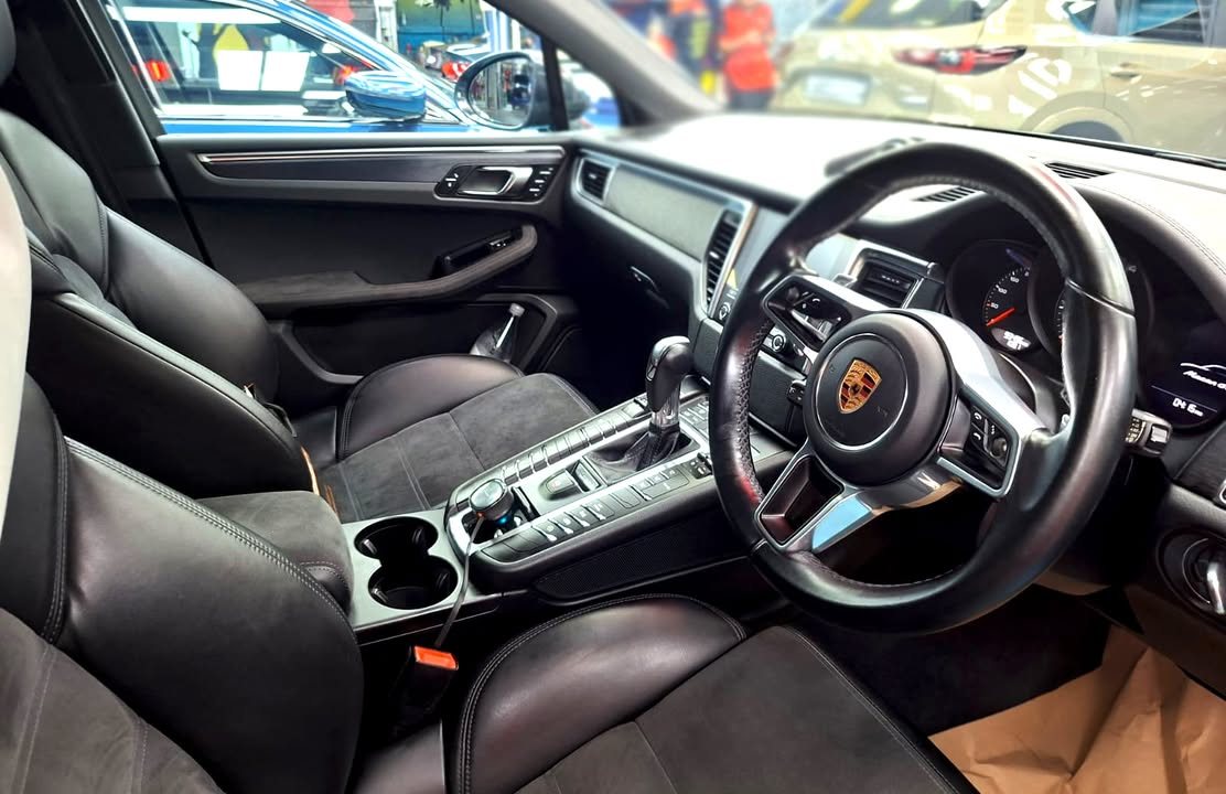 Porsche Macan front cabin with black seats and steering wheel.