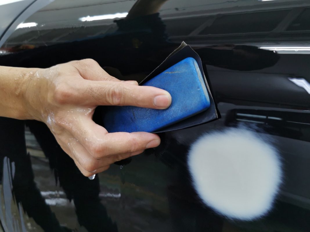 Wet-sanding the Panamera's panels to smooth the existing paintwork.