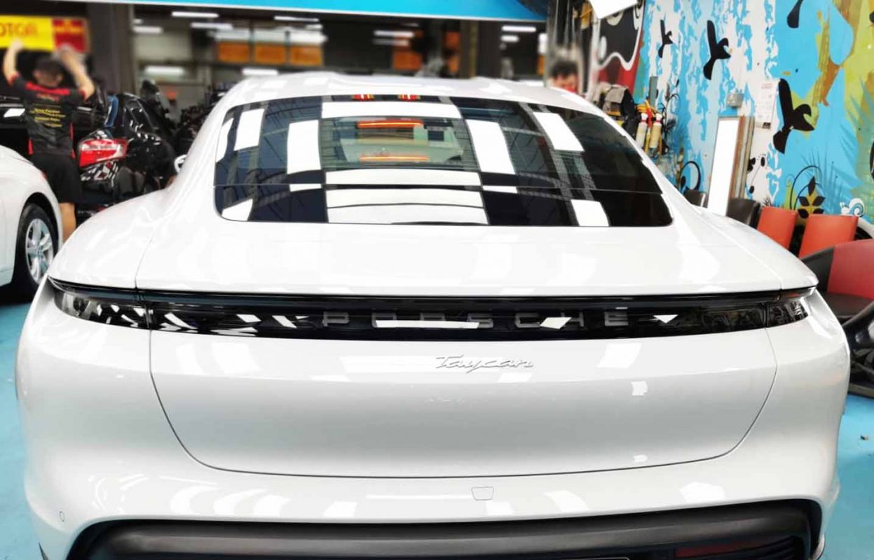 The coated bonnet of the Porsche Taycan under workshop lighting.