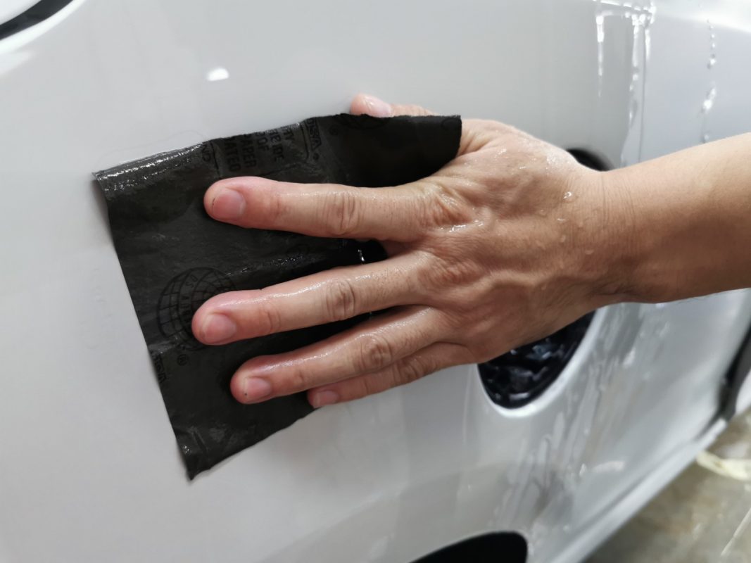 Wet-sanding the Megane's panels to smooth the existing paintwork.