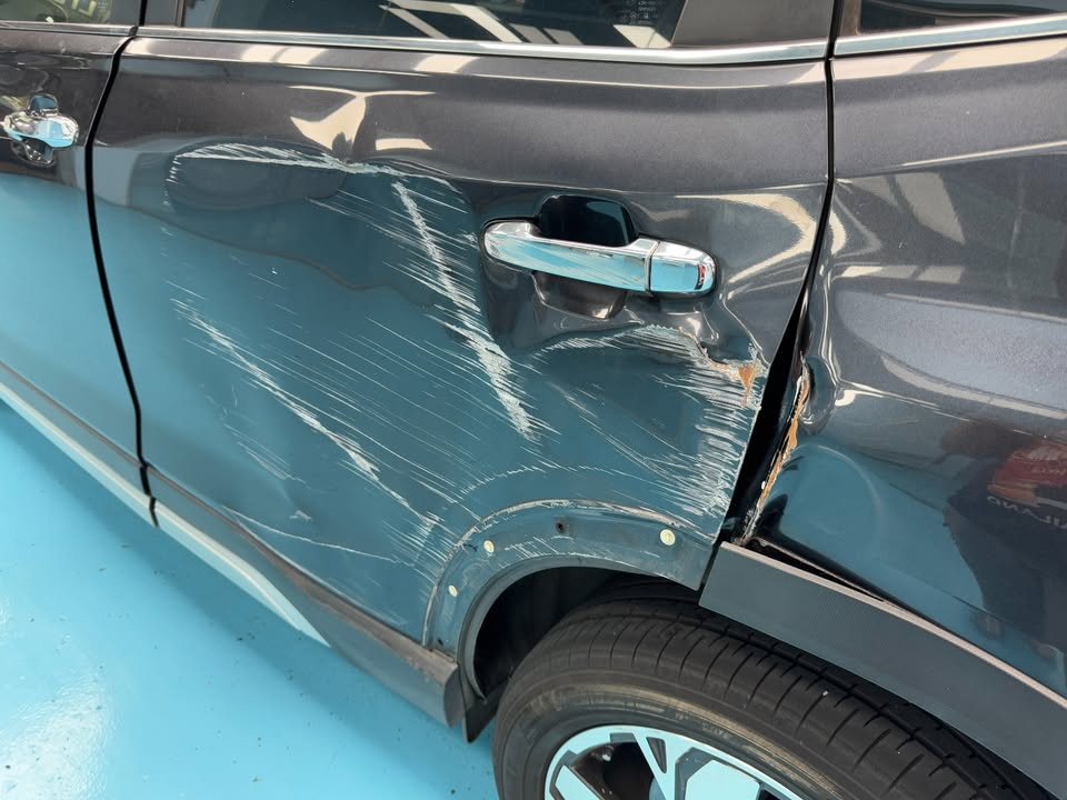 Deep scratches and a dent across the rear door and quarter panel of the Forester.