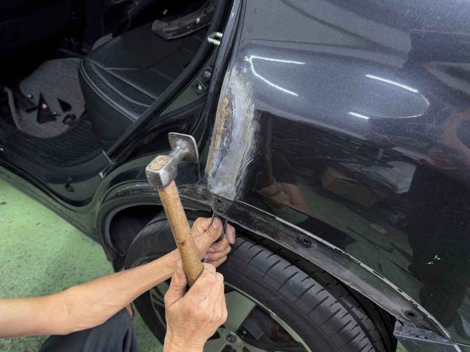 Hammer working the dented rear quarter panel behind the door.