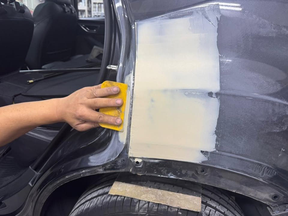 Sanding cream filler on the rear quarter panel of the Forester.