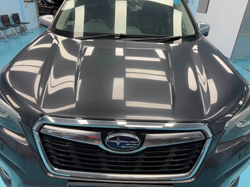 Front view of the finished Forester's bonnet and grille reflecting the workshop lights.
