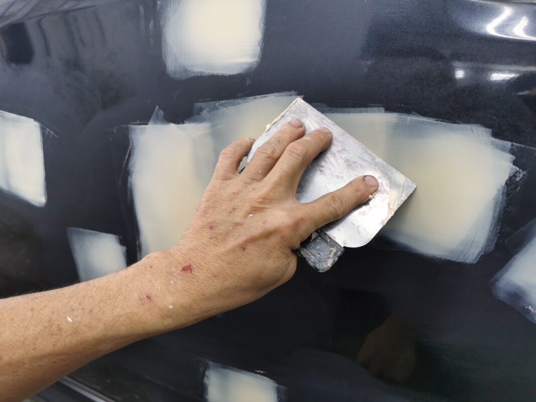 Surface repair work on the Subaru Forester, smoothing damaged areas before painting.