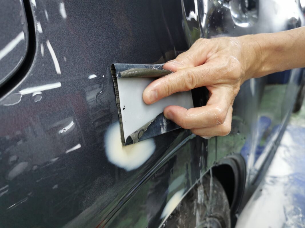Wet-sanding the Subaru Forester's panels to level the surface before priming.
