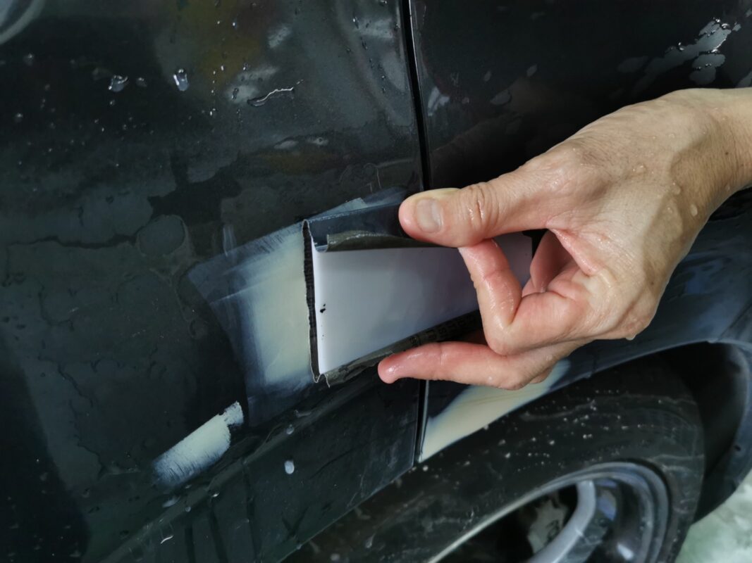 Wet-sanding a panel on the Subaru Forester, working the surface smooth.