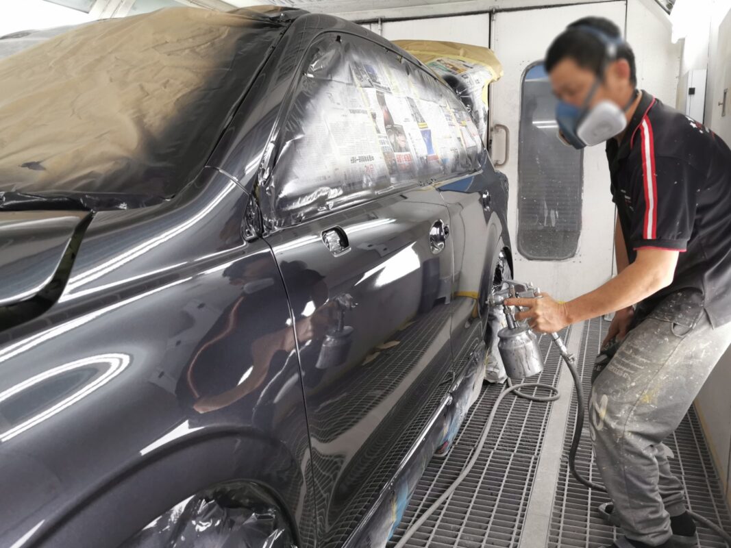 A Revol Carz painter spraying the new coat onto the Subaru Forester in the spray booth.