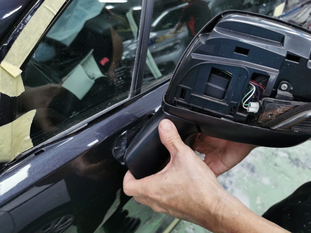 Parts being refitted onto the Subaru Forester during reassembly after painting.