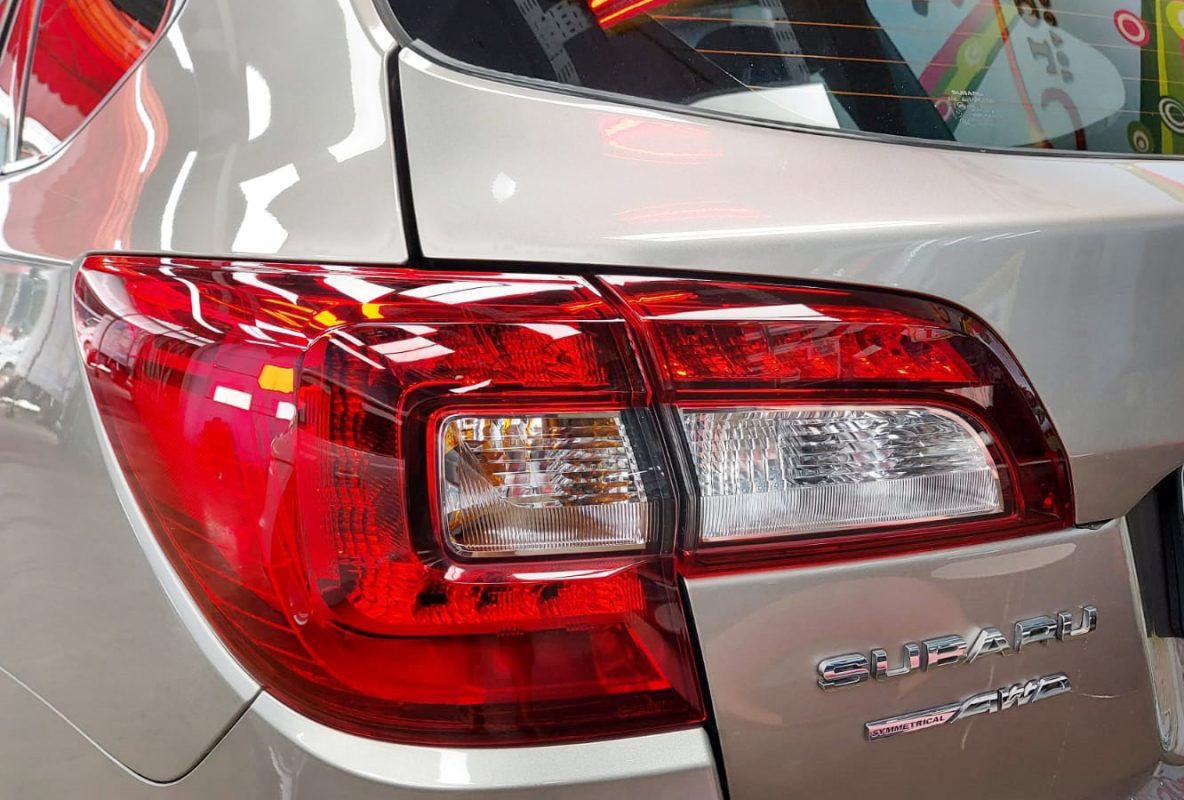 The coated bonnet of the Subaru Outback under workshop lighting.