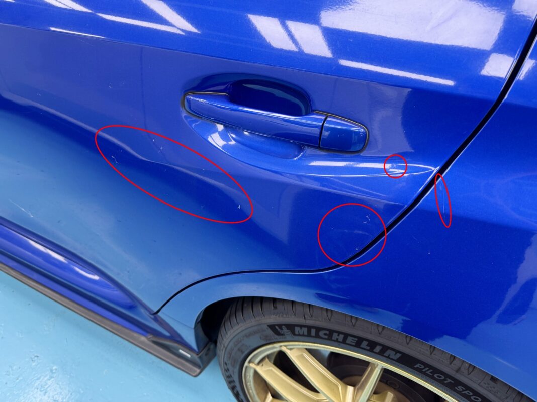 The Subaru WRX from another angle at intake, showing the damaged paintwork.
