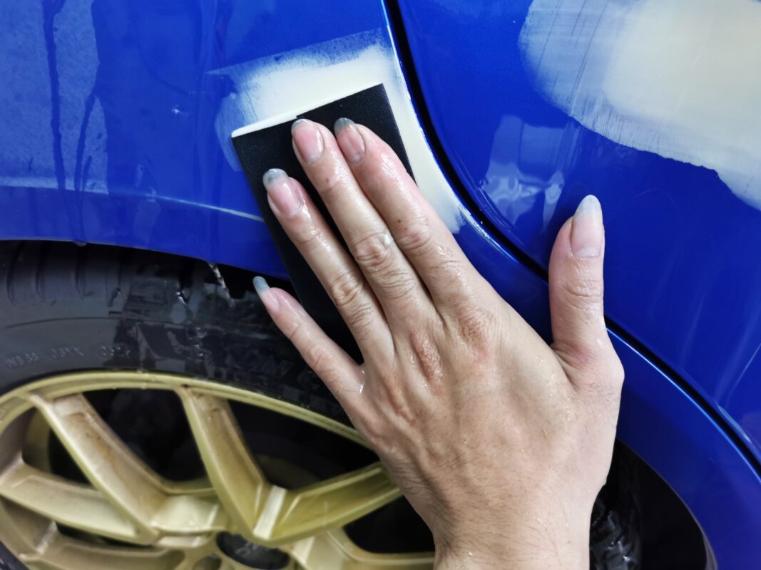 Wet-sanding the body of the Subaru WRX to smooth the surface.