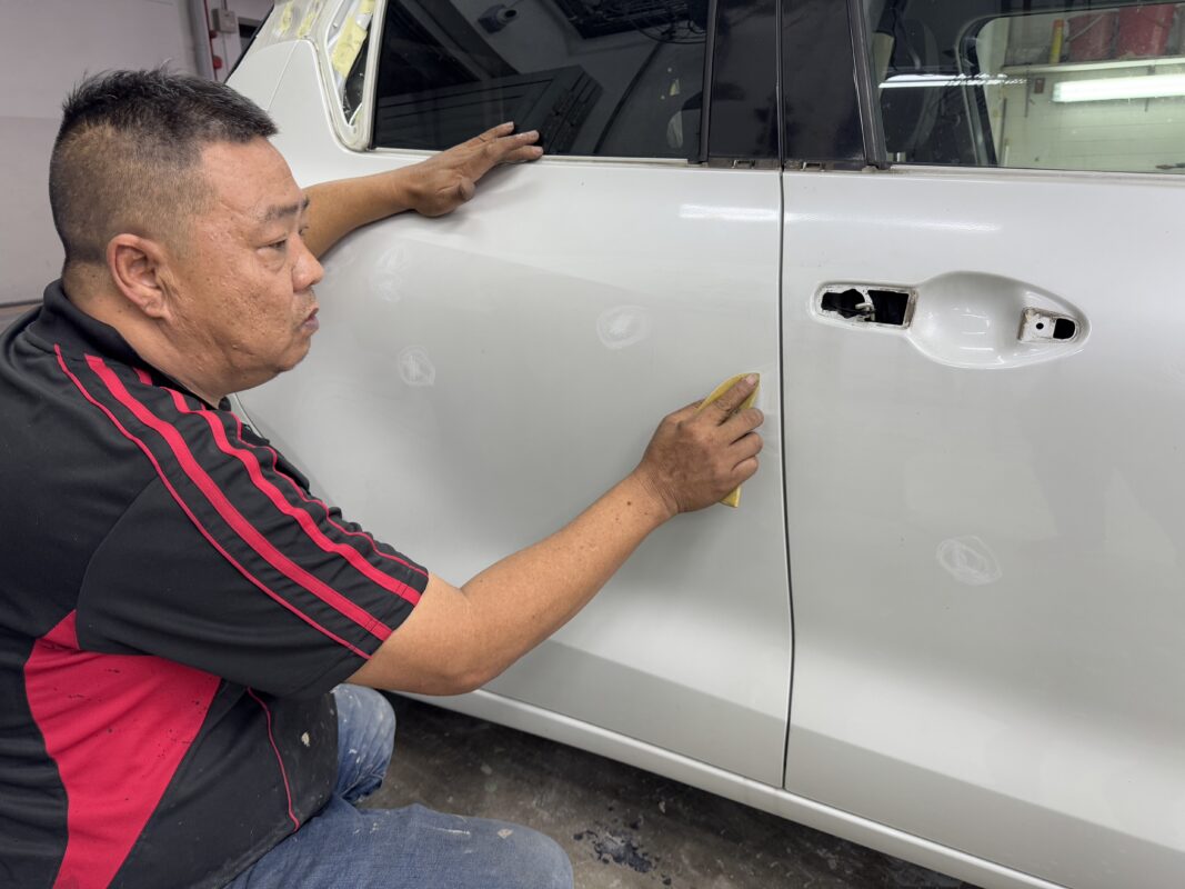 A technician applying filler and carrying out panel repairs on the Suzuki Swift.