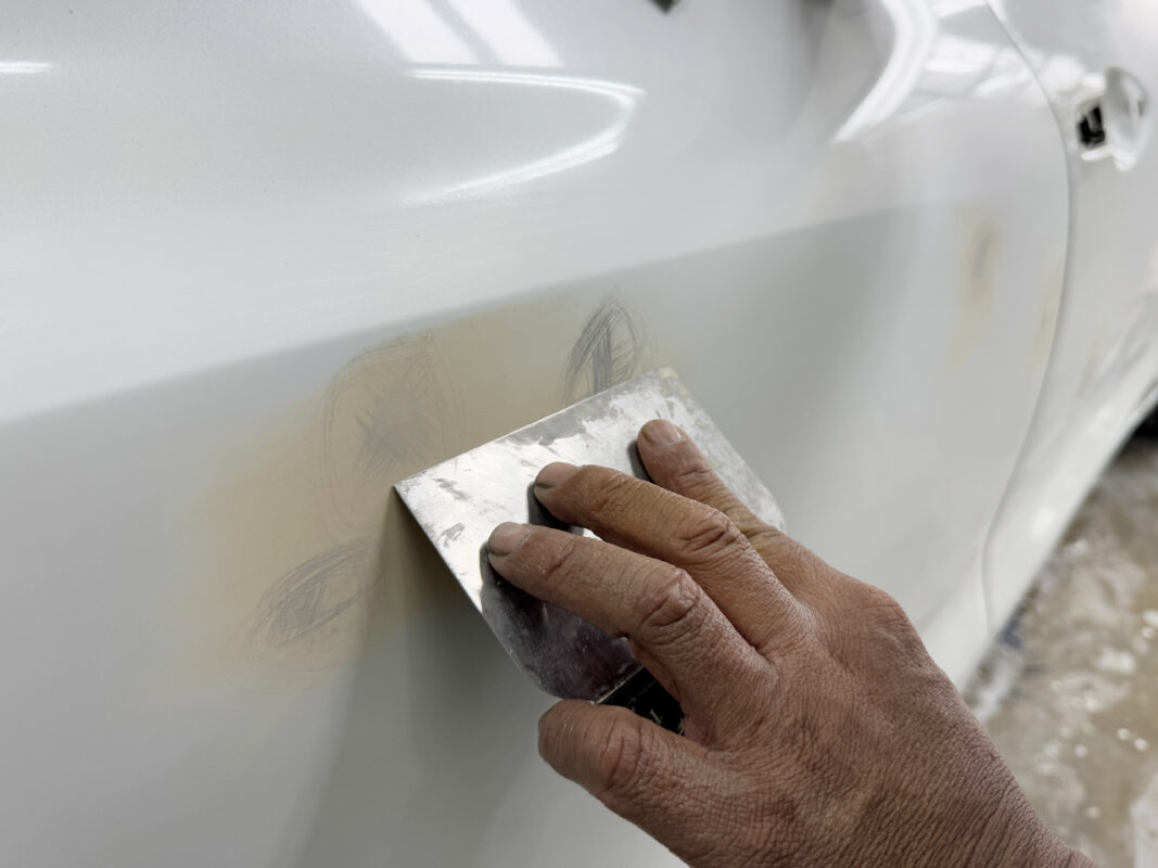 Wet-sanding a panel on the Suzuki Swift to bring the surface smooth and level.