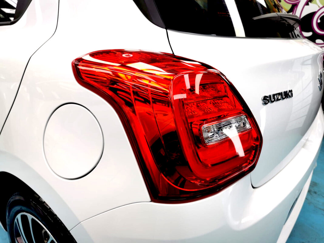 The coated bonnet of the Suzuki Swift under workshop lighting.
