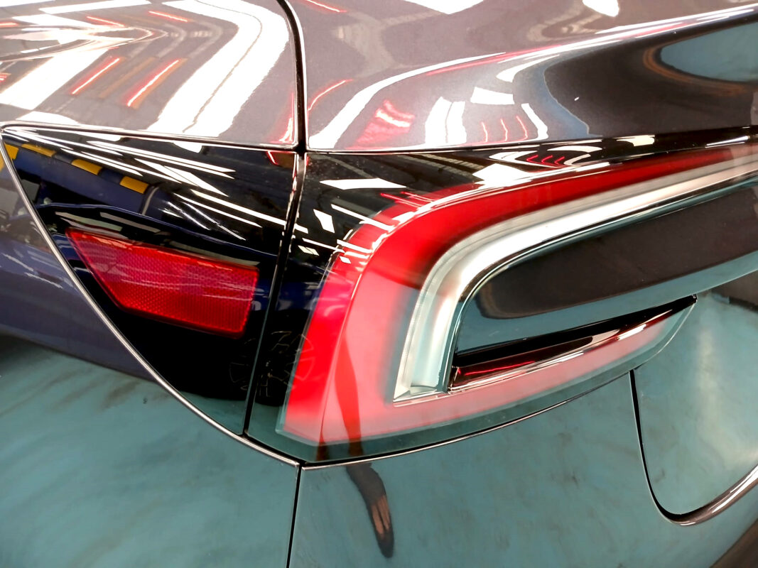 The coated bonnet of the Tesla Model 3 under workshop lighting.