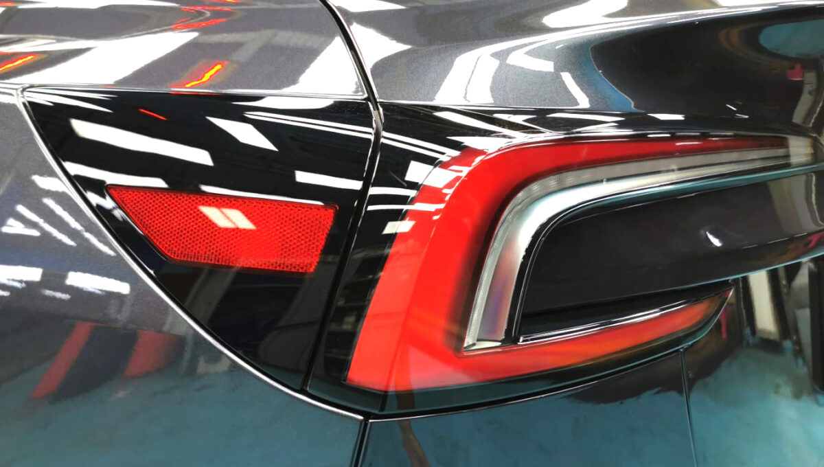 The coated bonnet of the Tesla Model 3 under workshop lighting.