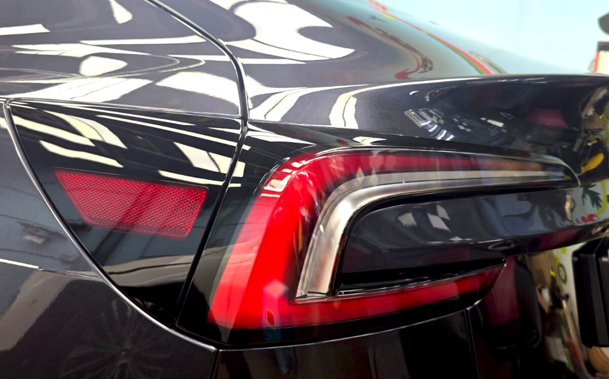 The coated bonnet of the Tesla Model 3 under workshop lighting.