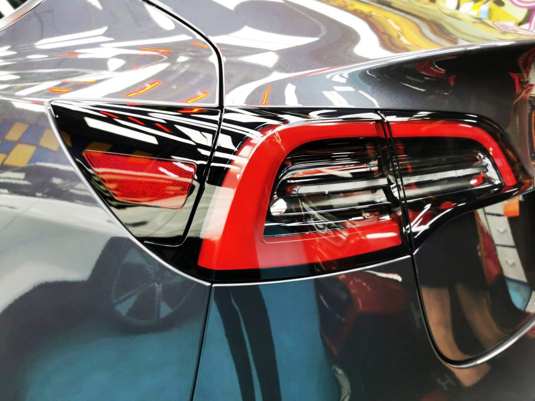 The coated bonnet of the Tesla Model 3 under workshop lighting.