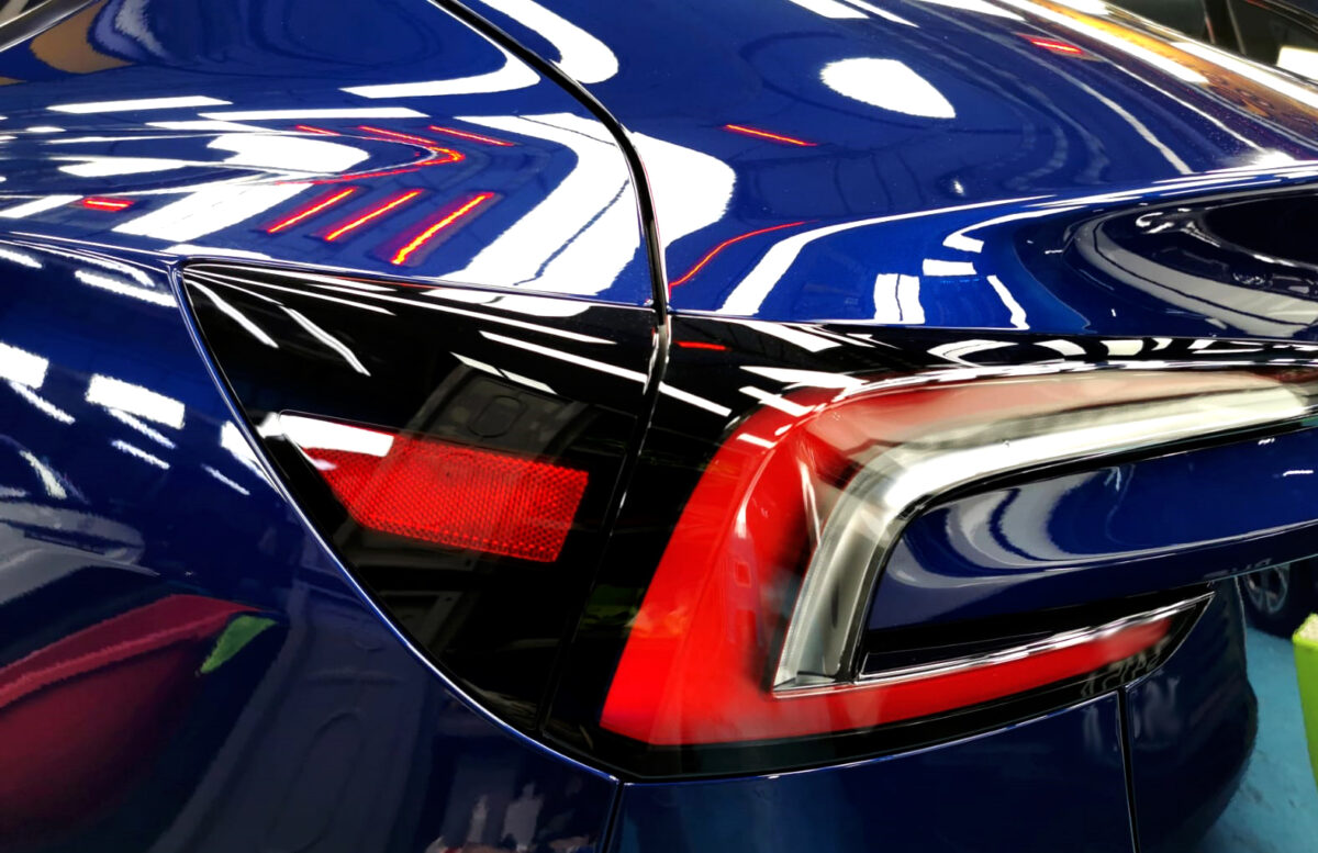The coated bonnet of the Tesla Model 3 under workshop lighting.