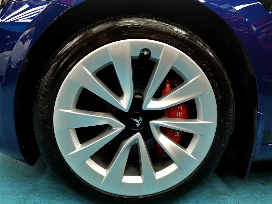 The coated bonnet of the Tesla Model 3 under workshop lighting.