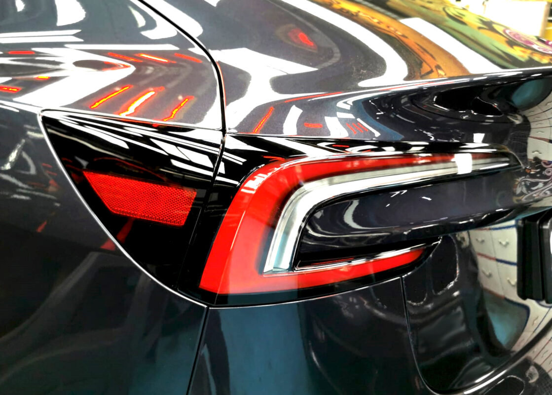 The coated bonnet of the Tesla Model 3 under workshop lighting.