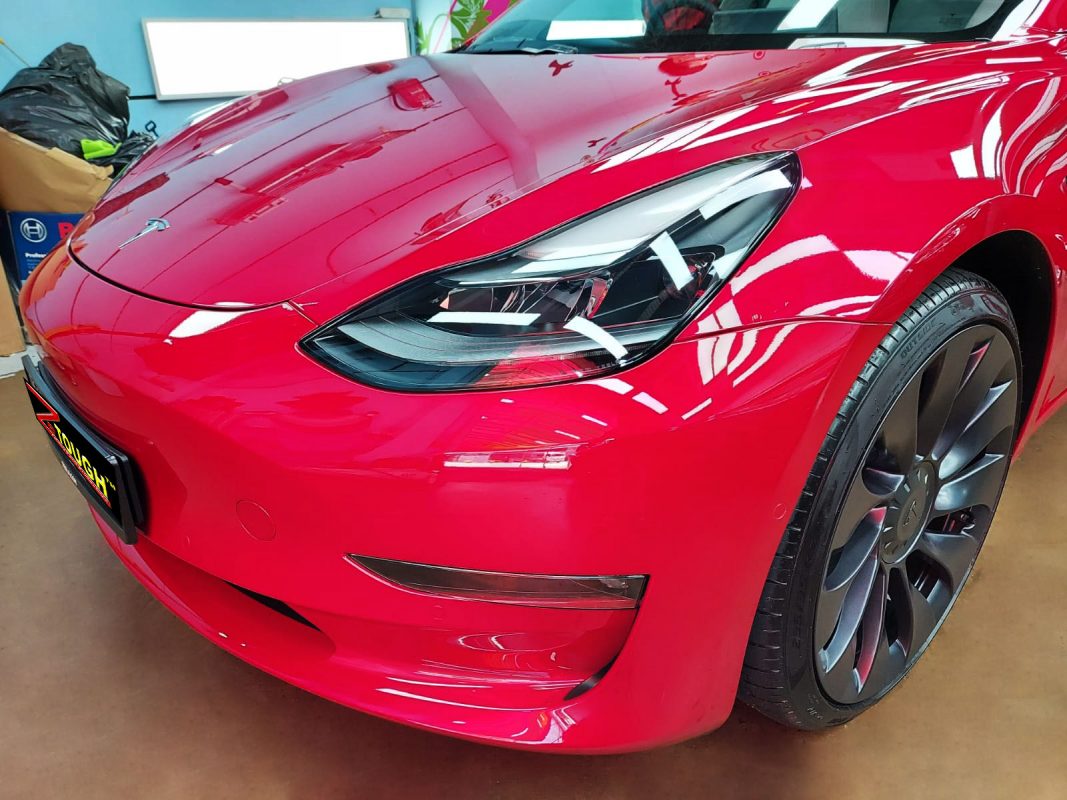 The red Tesla Model 3 from a side angle after the titanium coating.