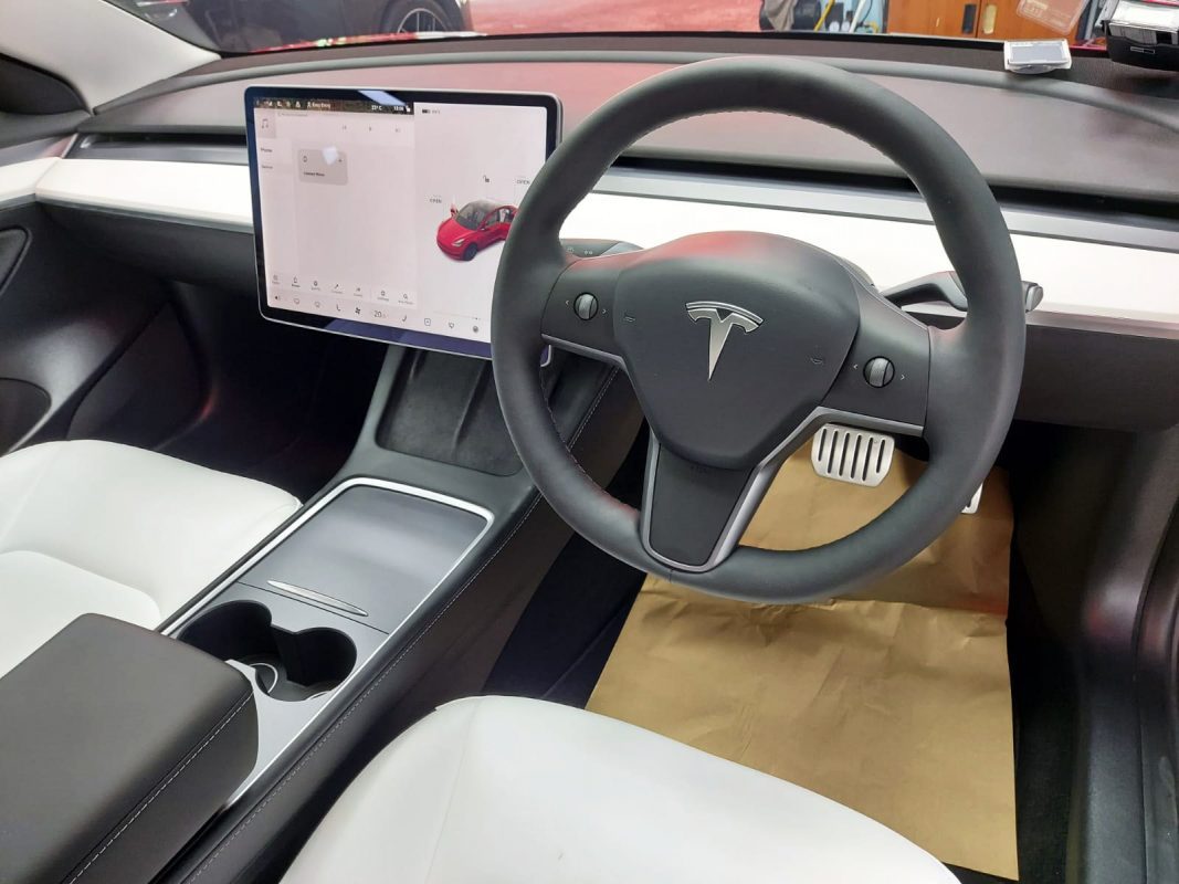 The red Tesla Model 3 parked in the workshop, freshly coated.