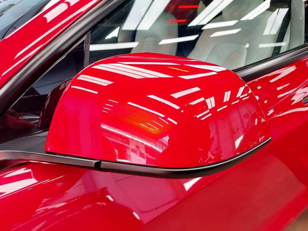 Side panel of the red Tesla Model 3 with the titanium finish locked in.