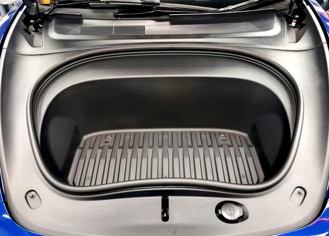 Reflections across the coated panels of the Tesla Model 3.